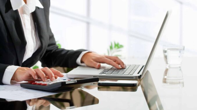 Female office worker doing accounting with calculator.
