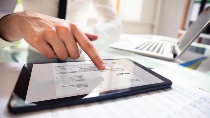 Businessperson Analyzing Invoice On Digital Tablet